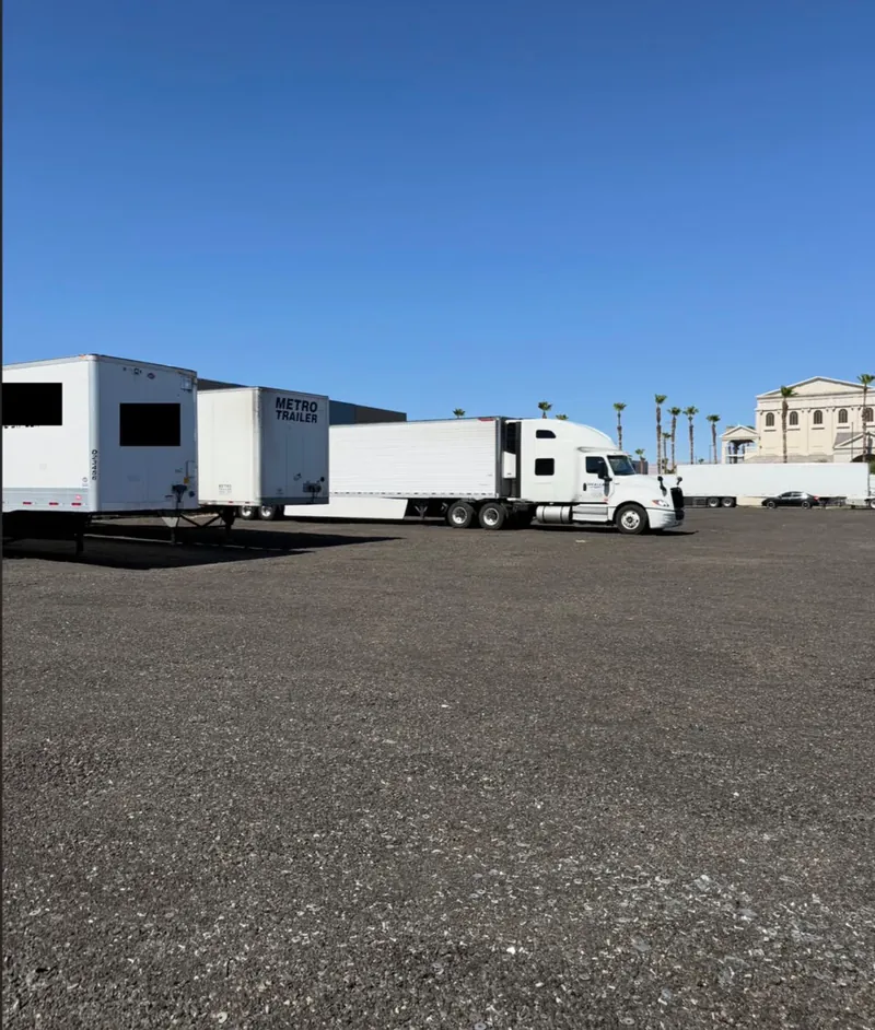 Semi trucks and 53-foot trailers parked on the graded gravel lot at the Bounds & Peaks Strip Yard, secure truck parking in Las Vegas